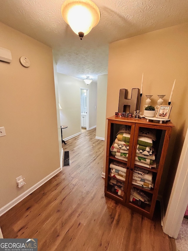 hall with hardwood / wood-style floors and a textured ceiling