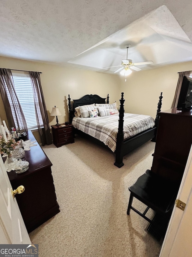 carpeted bedroom with ceiling fan and a textured ceiling