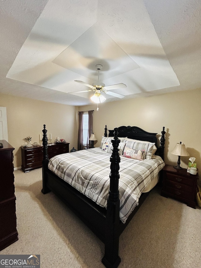 carpeted bedroom featuring a tray ceiling and ceiling fan