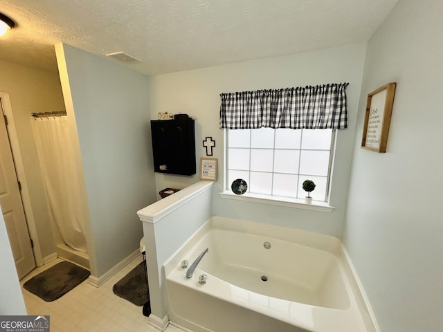 bathroom featuring a textured ceiling and shower with separate bathtub