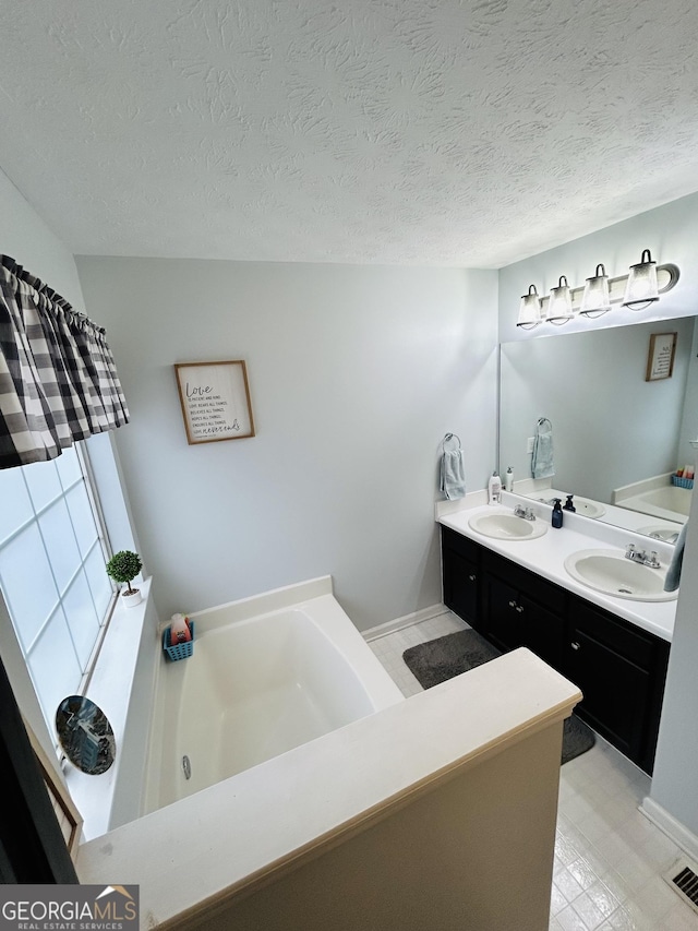 bathroom featuring a bathtub, a textured ceiling, and vanity