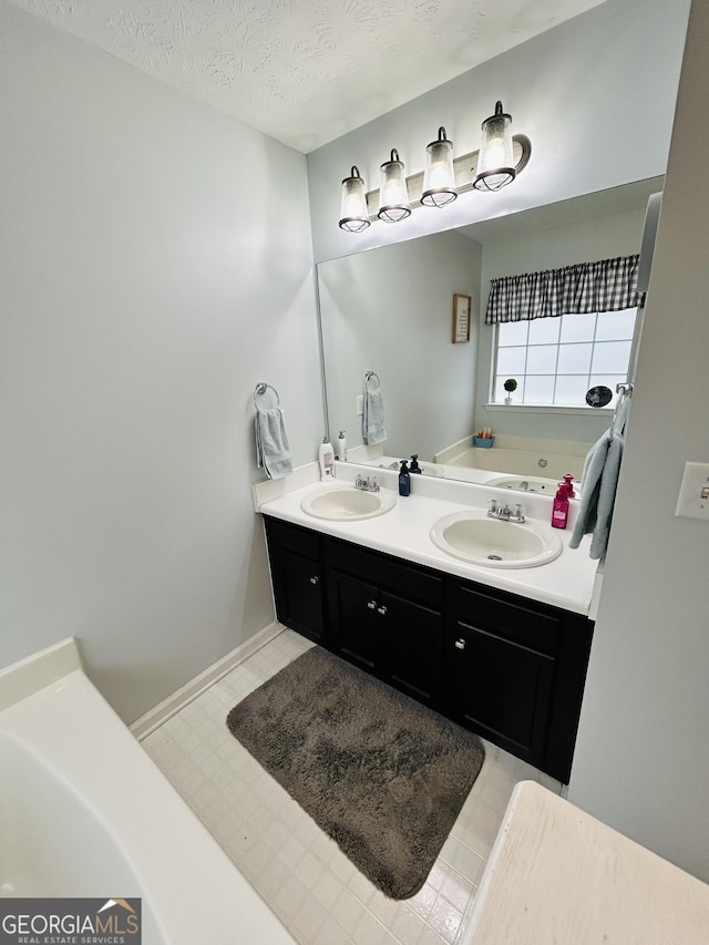 bathroom featuring vanity, a washtub, and a textured ceiling