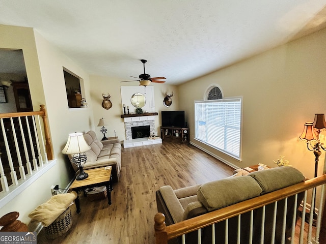 living room featuring ceiling fan, hardwood / wood-style floors, and a fireplace