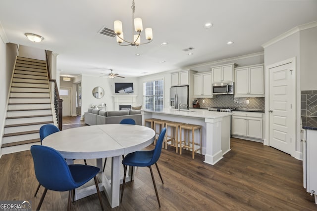 dining area with dark hardwood / wood-style flooring, crown molding, and ceiling fan with notable chandelier