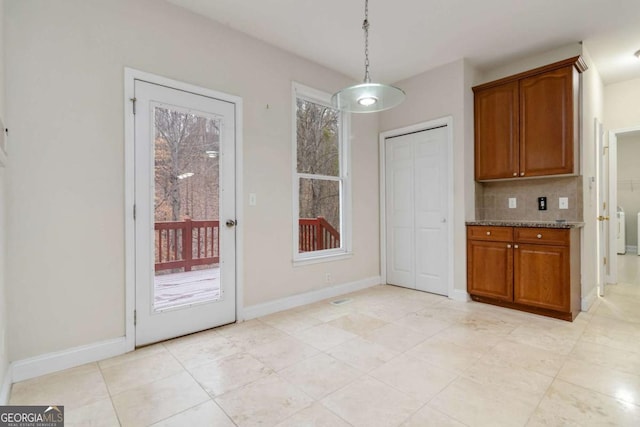 kitchen featuring backsplash, light stone countertops, and decorative light fixtures