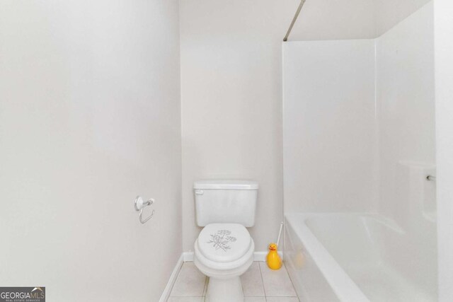 bathroom with toilet, a bathing tub, and tile patterned flooring