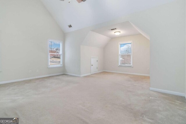 additional living space with ceiling fan, light colored carpet, and lofted ceiling