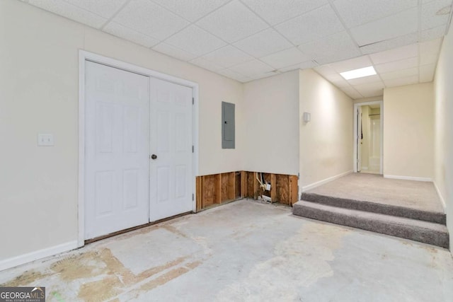 spare room with a paneled ceiling, concrete floors, and electric panel