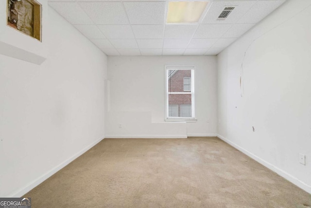 carpeted empty room featuring a drop ceiling