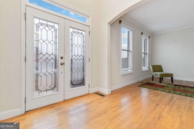 entrance foyer with french doors, light wood-type flooring, and ornamental molding