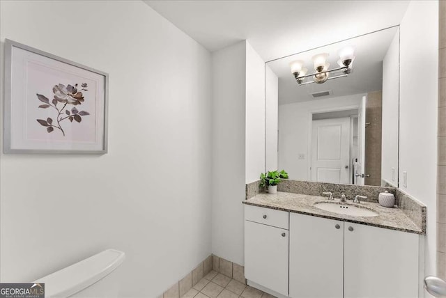 bathroom with tile patterned floors, vanity, toilet, and a notable chandelier