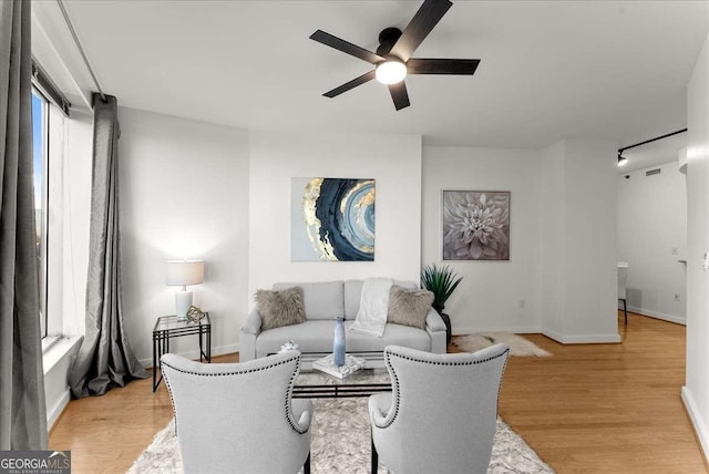 living room with light wood-type flooring, a healthy amount of sunlight, and ceiling fan