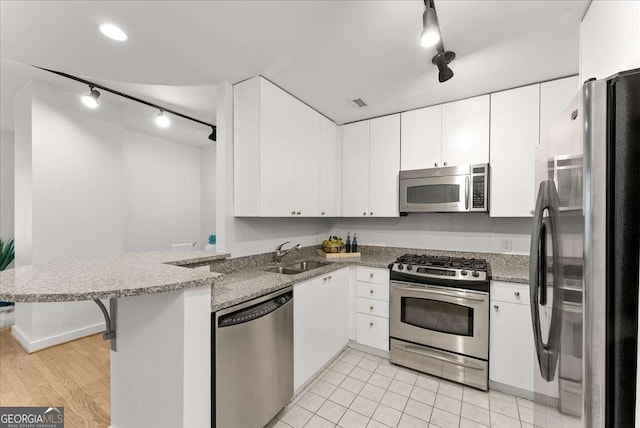 kitchen with kitchen peninsula, sink, white cabinetry, and stainless steel appliances