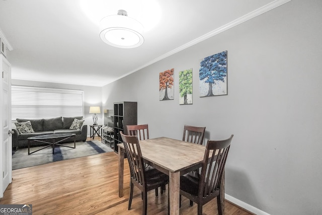 dining space with crown molding and wood-type flooring