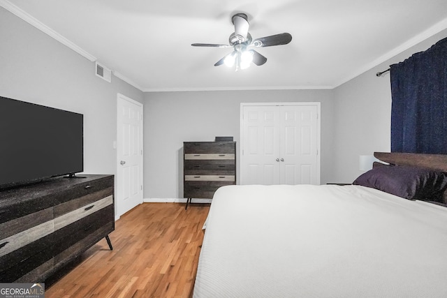 bedroom featuring light wood-type flooring, ceiling fan, ornamental molding, and a closet