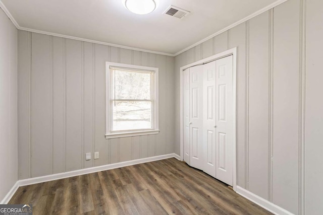 unfurnished bedroom featuring a closet, ornamental molding, and dark hardwood / wood-style flooring