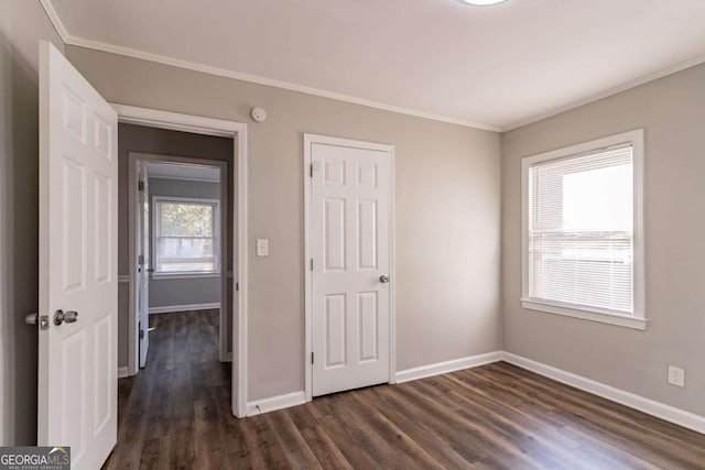 unfurnished bedroom with dark wood-type flooring, a closet, and ornamental molding