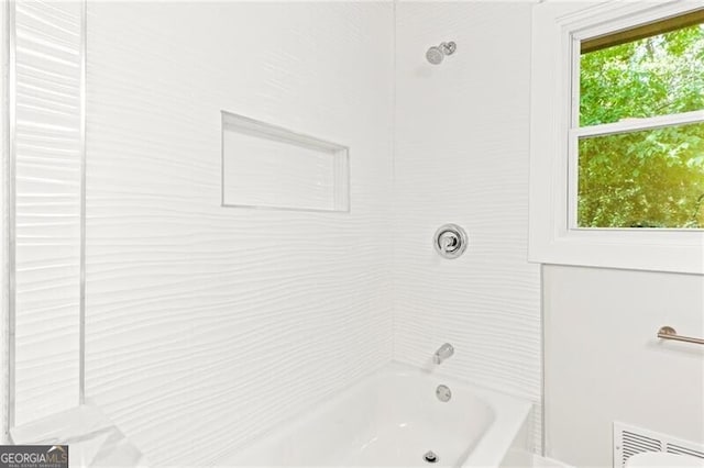 bathroom featuring plenty of natural light and tiled shower / bath combo