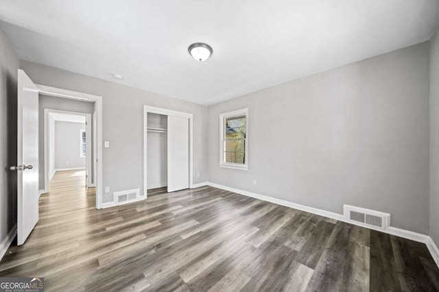 unfurnished bedroom with dark hardwood / wood-style floors and a closet