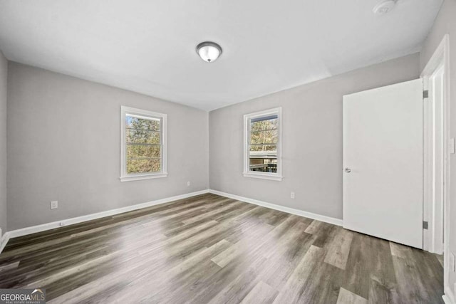 empty room featuring plenty of natural light and dark wood-type flooring