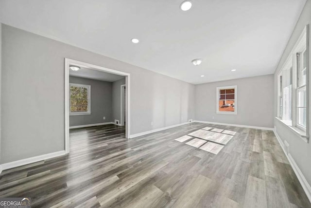 spare room featuring plenty of natural light and dark hardwood / wood-style flooring
