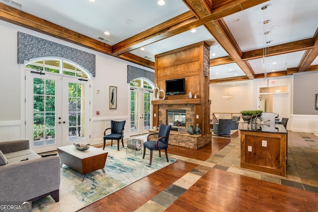 living room featuring french doors, a fireplace, light hardwood / wood-style flooring, and beamed ceiling