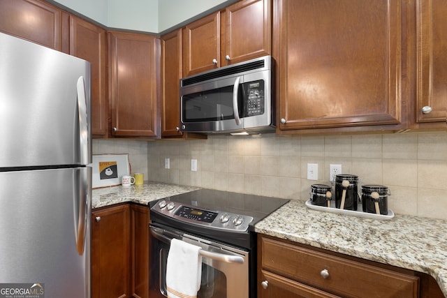 kitchen with light stone counters, decorative backsplash, and stainless steel appliances