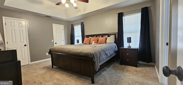 carpeted bedroom featuring a raised ceiling and ceiling fan