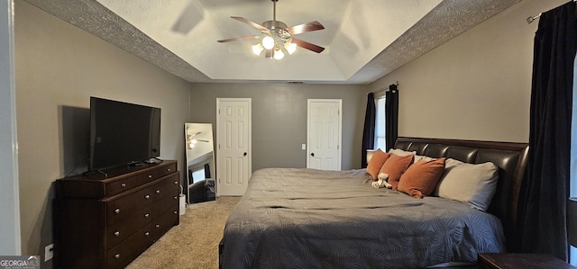 carpeted bedroom with a tray ceiling, a textured ceiling, and ceiling fan