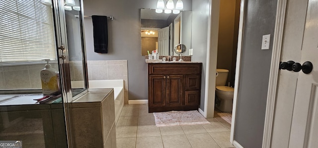 bathroom with tile patterned floors, toilet, vanity, and tiled tub