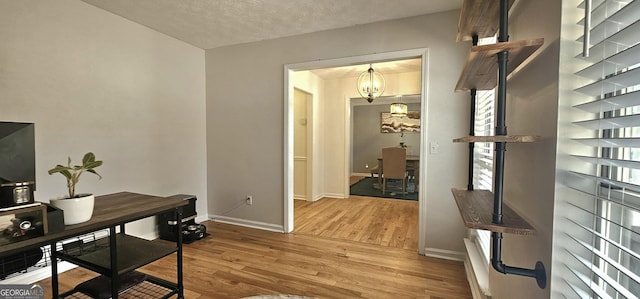 office area with an inviting chandelier, hardwood / wood-style flooring, and a textured ceiling