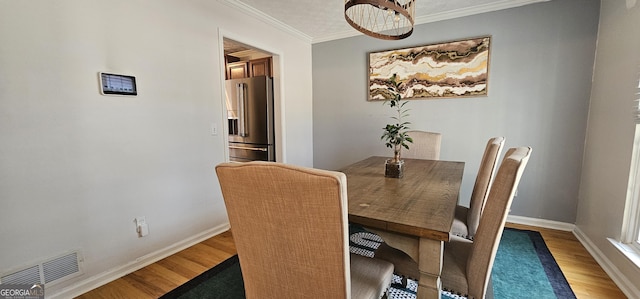 dining room with crown molding and hardwood / wood-style flooring