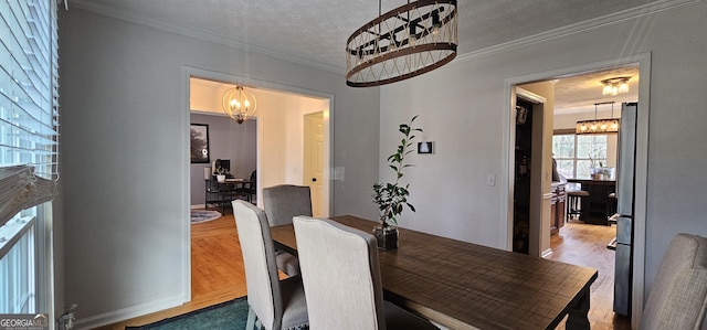 dining room with hardwood / wood-style floors, a notable chandelier, ornamental molding, and a textured ceiling