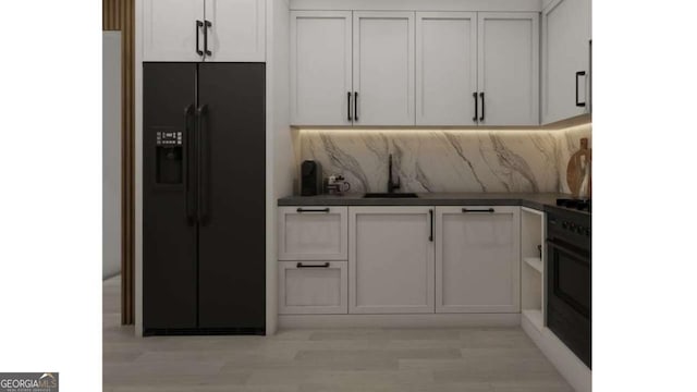 kitchen with black appliances, white cabinetry, tasteful backsplash, and sink