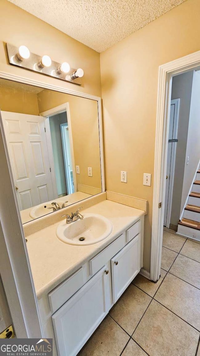 bathroom with a textured ceiling, tile patterned flooring, and vanity