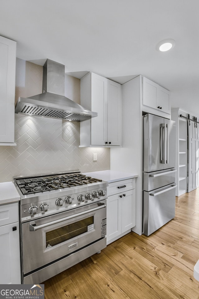 kitchen with white cabinetry, wall chimney exhaust hood, and appliances with stainless steel finishes