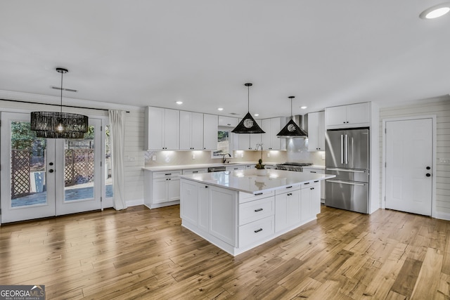 kitchen with pendant lighting, stainless steel refrigerator, white cabinets, and a center island