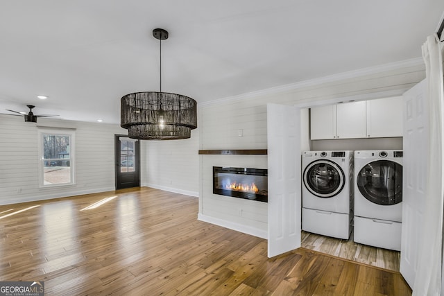 laundry area featuring cabinets, crown molding, washer and clothes dryer, and light hardwood / wood-style floors