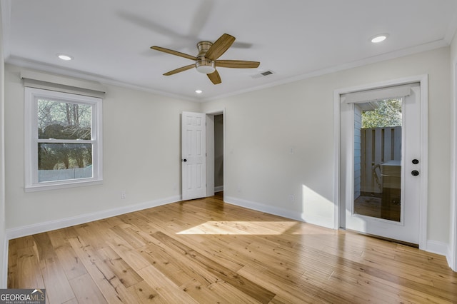 spare room featuring a wealth of natural light, ornamental molding, and light hardwood / wood-style floors