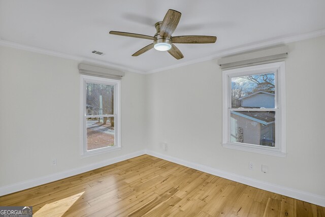 spare room with crown molding, ceiling fan, wood-type flooring, and a wealth of natural light