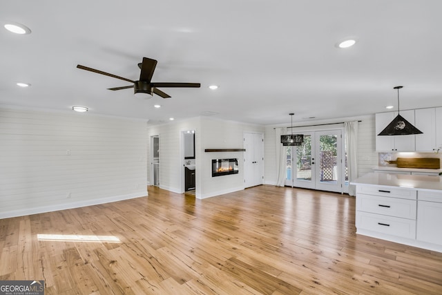 unfurnished living room featuring french doors, ceiling fan, and light wood-type flooring