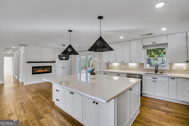 kitchen featuring sink, decorative light fixtures, white cabinets, and a kitchen island