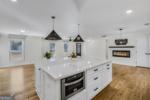 kitchen featuring oven, a center island, white cabinets, and decorative light fixtures