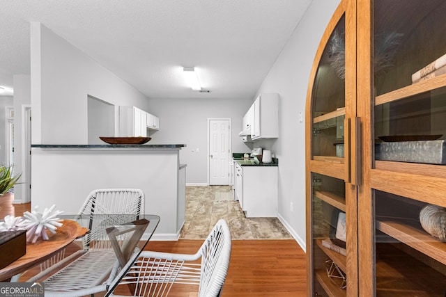 kitchen featuring white cabinetry, stove, a textured ceiling, and light wood-type flooring