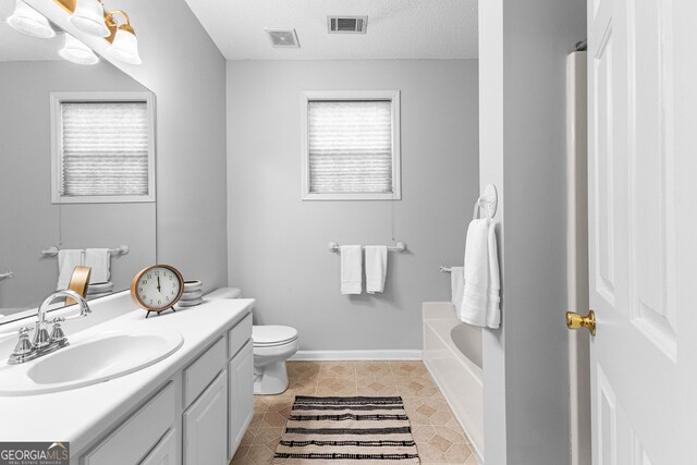 bathroom with vanity, a washtub, toilet, and a textured ceiling