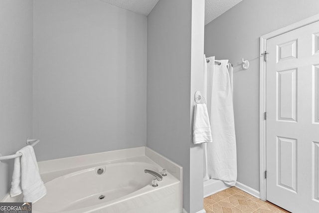 bathroom featuring tile patterned flooring, a bath, and a textured ceiling