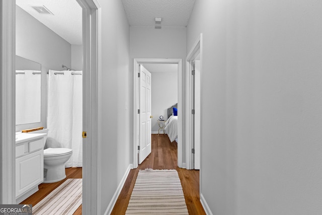 hall with wood-type flooring and a textured ceiling