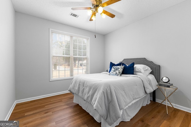 bedroom featuring hardwood / wood-style flooring, ceiling fan, and a textured ceiling