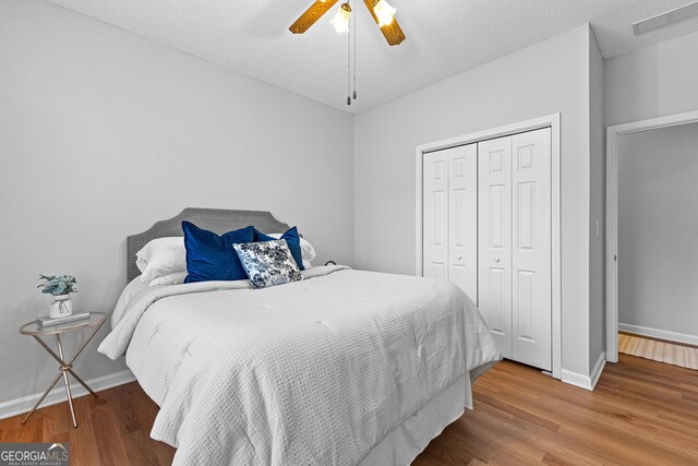 bedroom with ceiling fan, wood-type flooring, a closet, and a textured ceiling