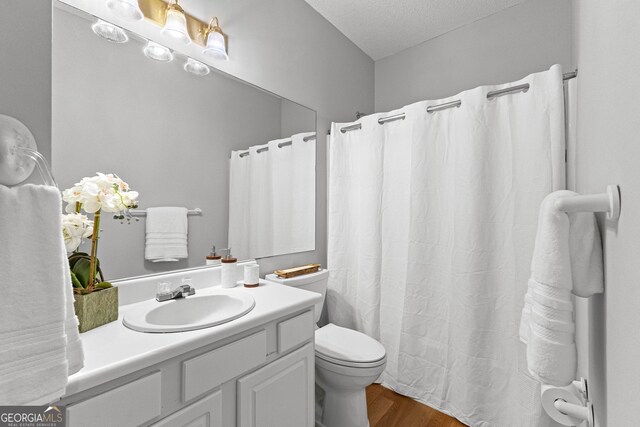 bathroom with hardwood / wood-style flooring, vanity, a textured ceiling, and toilet